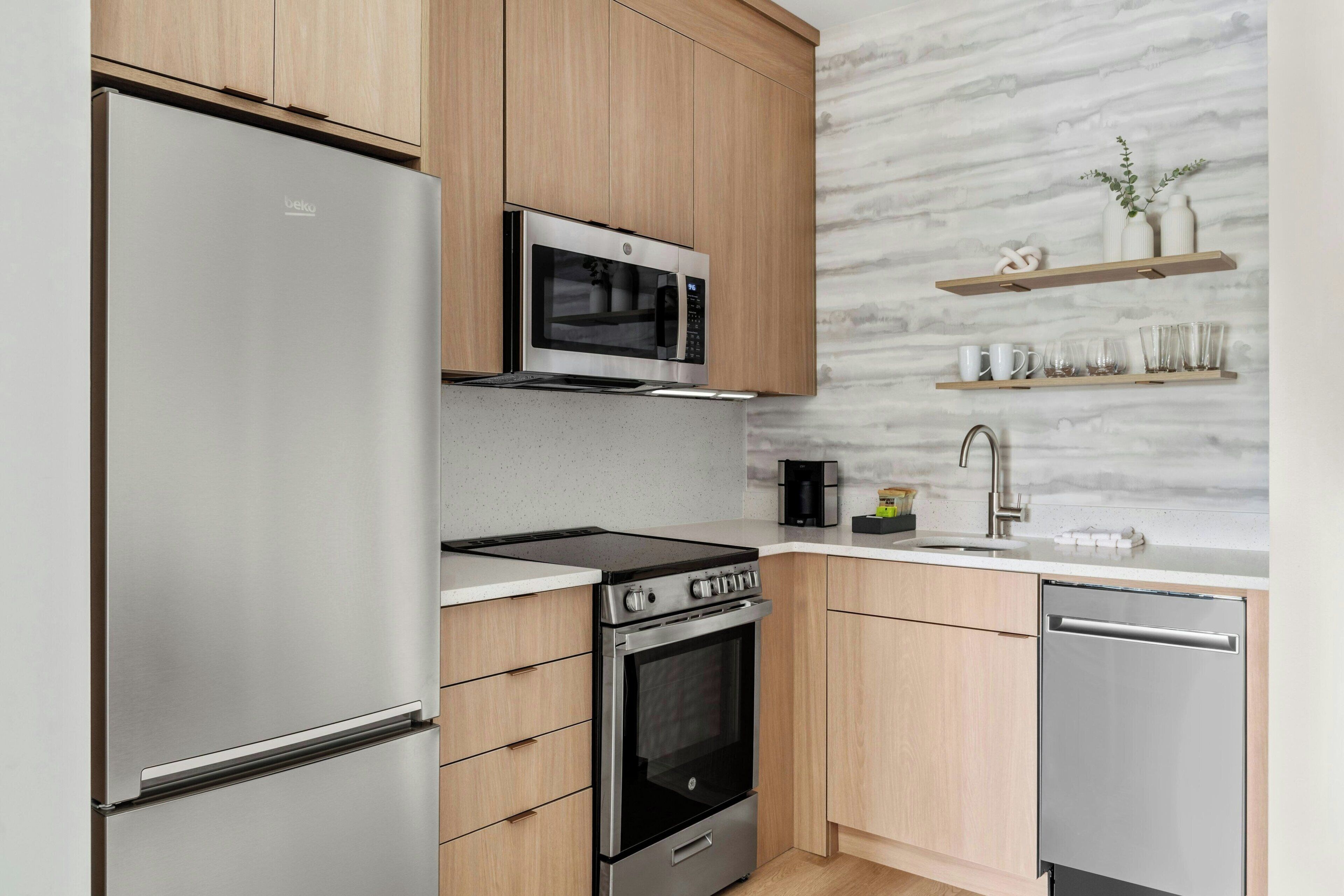 Une cuisine moderne dotée d’appareils électroménagers en acier inoxydable, de meubles en bois et d’un dosseret en marbre.
