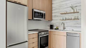 A modern kitchen with stainless steel appliances, wooden cabinets, and a marble backsplash.