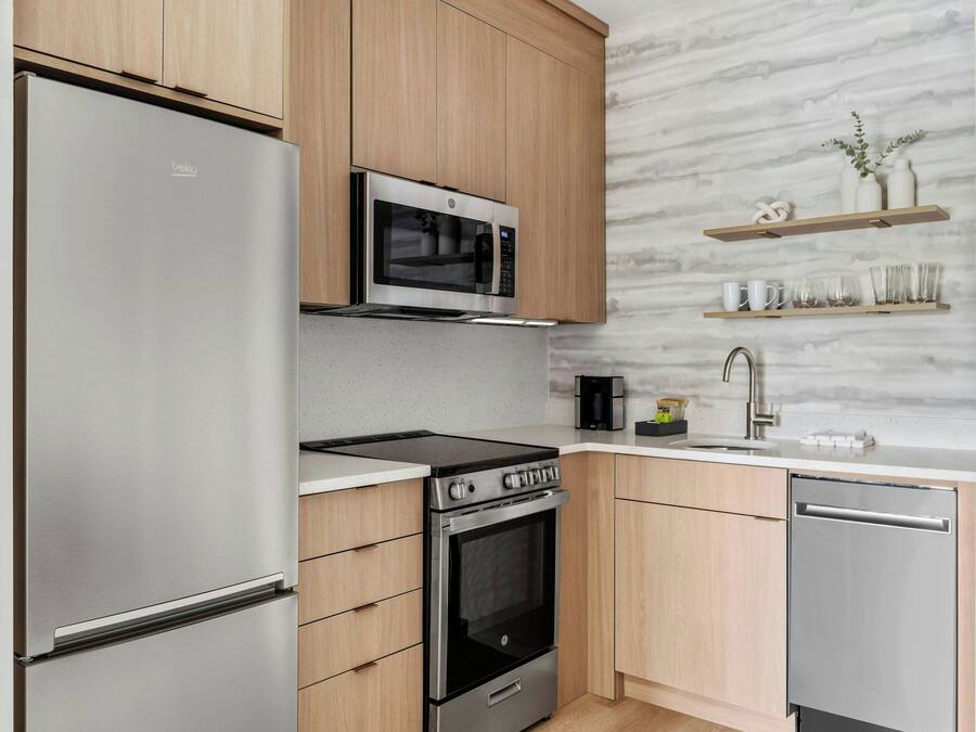 A modern kitchen with stainless steel appliances, wooden cabinets, and a marble backsplash.