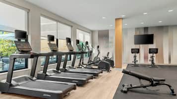 A gym with treadmills, exercise bikes, and a bench.