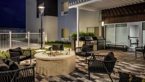Eine Außenpatio mit Feuerstelle, Sitzgelegenheiten und Grillbereich.