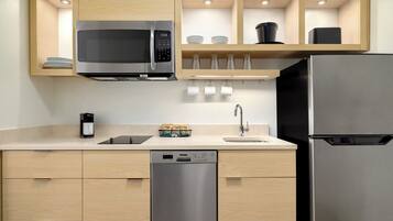 A modern kitchen with a built-in microwave, a stainless steel refrigerator, and a dishwasher.