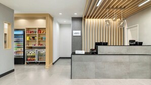 Eine Hotelrezeption im modernen Stil, mit einer Rezeption, einer Minibar und einem Selbstbedienungsgetränkeautomaten.
