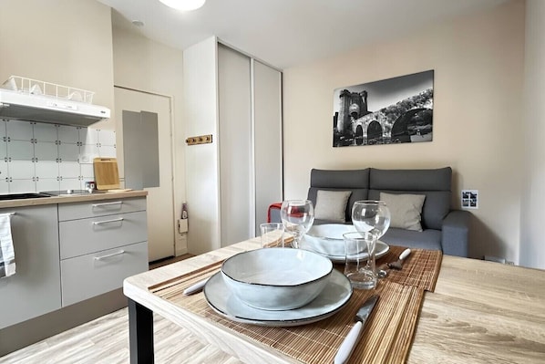 A modern kitchen with a dining area, a sofa, and a painting on the wall.