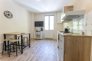 A compact kitchen with a wooden countertop, a microwave, and a TV.