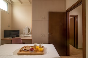 A bedroom with a bed, a desk with a computer, a wardrobe, and a breakfast tray with bread, strawberries, and orange juice. - Posto Serene With Jacuzzi (Minoa Pediada)