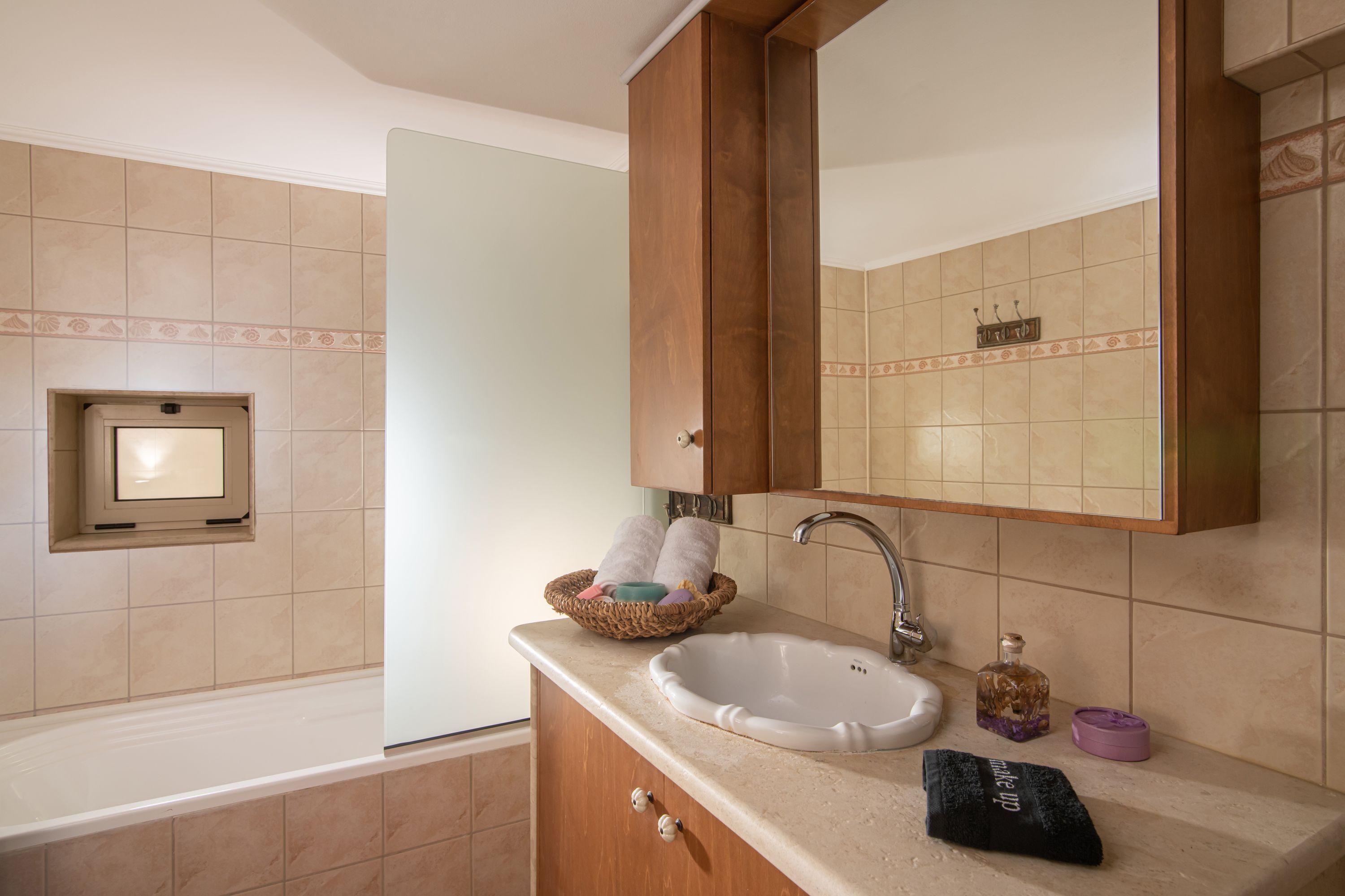 A bathroom with a white sink, a mirror, and a wooden cabinet.