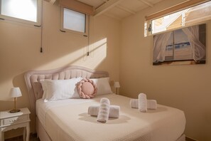 Une chambre à coucher avec un grand lit, une table de chevet, une lampe et une fenêtre avec des rideaux.