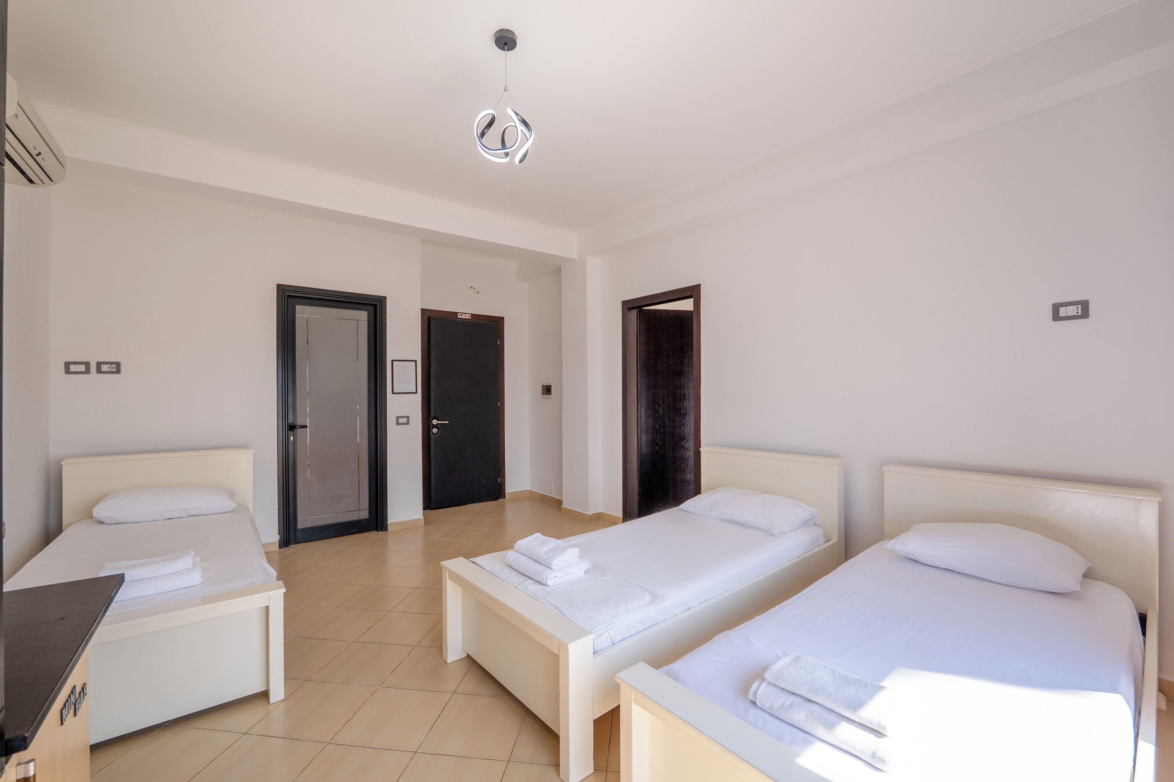 Hotellihuone, jossa on kaksi erillistä sänkyä, työpöytä ja vaatekaappi.