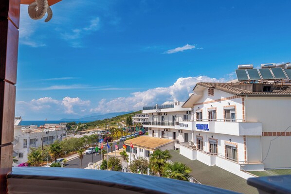 A hotel with a 'HOTEL' sign, solar panels on the roof, and a view of the sea and mountains in the background. - La Luna Resort (Ksamil)