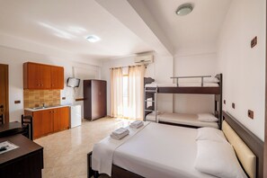 A compact hotel room with a kitchenette, a bed with two pillows, a small desk, and a television. - La Luna Resort (Ksamil)
