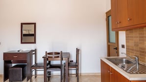 Une cuisine de taille réduite, dotée d’un évier, de meubles en bois et d’un coin repas avec des chaises et une table.