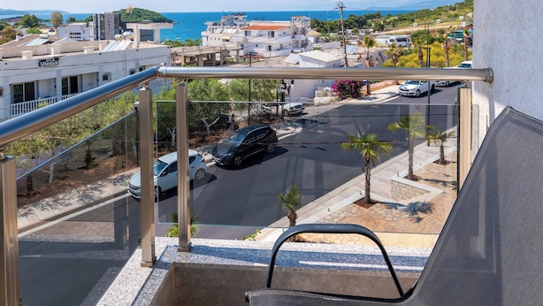 Un balcon avec vue sur la mer, un espace de stationnement et des bâtiments en arrière-plan.