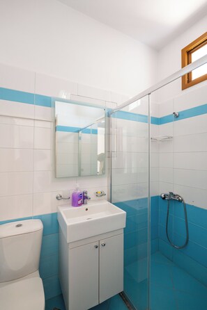 A bathroom with a white sink, a mirror, a shower, and blue-tiled walls. - La Luna Resort (Ksamil)