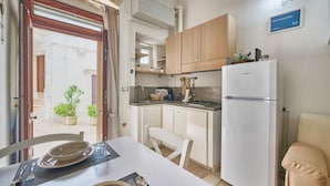 Een kleine keuken met een koelkast, fornuis en houten kastjes.
