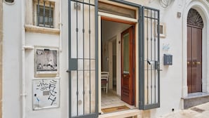 Een gebouw met een houten deur, een metalen poort en een deurmat.