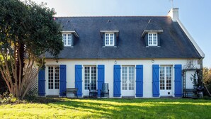 A two-story house with a sloped roof, multiple windows with shutters, and a front bench. - Family house with sea view / Beach 10min walk (Ploubazlanec)