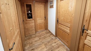 Un pasillo de madera con dos puertas, una con un estante y un cuadro en la pared.