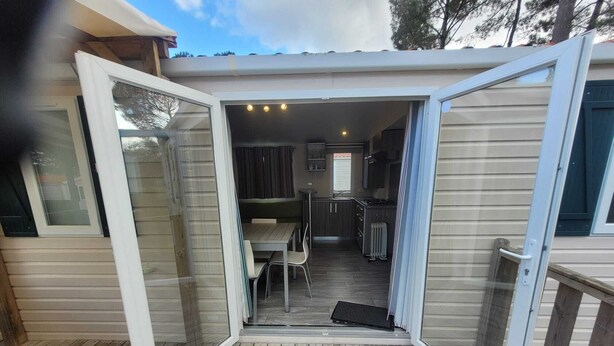 A covered outdoor area with a table and chairs, a small kitchen, and a sliding glass door.