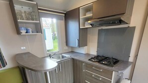 A compact kitchen with a gas stove, a sink, and wooden cabinets.