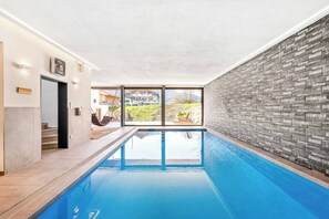 Piscina interior com vista para um edifício e uma parede de tijolos.