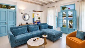 Een woonkamer met een blauwe bank, een ronde salontafel en een oranje fauteuil.
