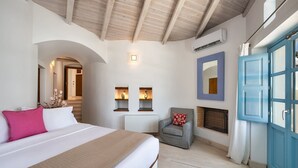 Een slaapkamer met een bed, een stoel, een open haard en een blauwe deur.