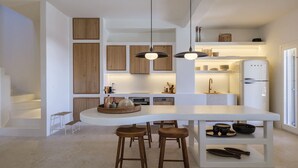 A modern kitchen with a central island, wooden cabinets, pendant lighting, and a built-in refrigerator.