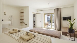 A modern bedroom with a large bed, a bedside table, a TV, and a view of the outdoors.