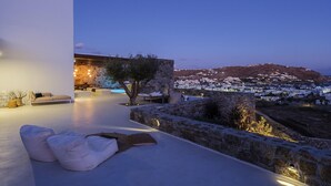 A modern outdoor seating area with a stone wall, a tree, and a view of a town in the background.