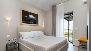Un dormitorio moderno con una cama grande, una mesita de noche con adornos, un cuadro de nubes y vistas a través de un ventanal.