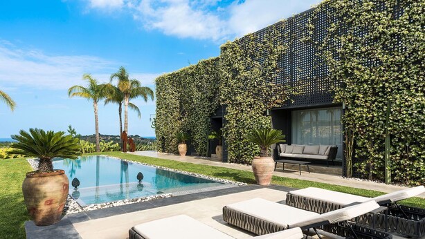 Un área de piscina moderna al aire libre con sillones de descanso y vista al océano.
