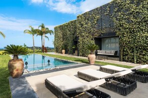 A modern outdoor pool area with lounge chairs and a view of the ocean. - Villa Monica with private pool - My Rental Homes (Noto)