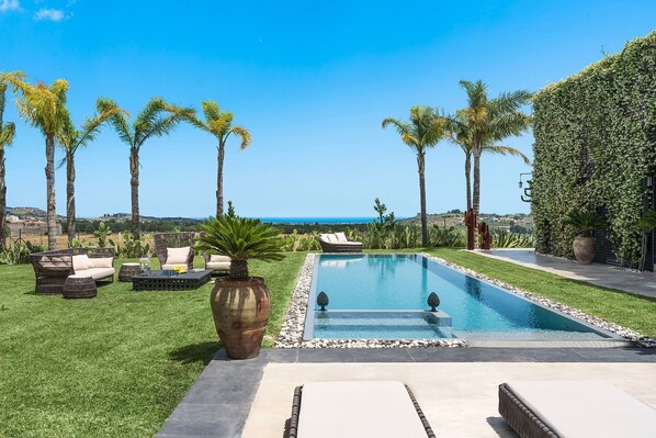 A pool area with lounge chairs and a view of the ocean. - Villa Monica with private pool - My Rental Homes (Noto)