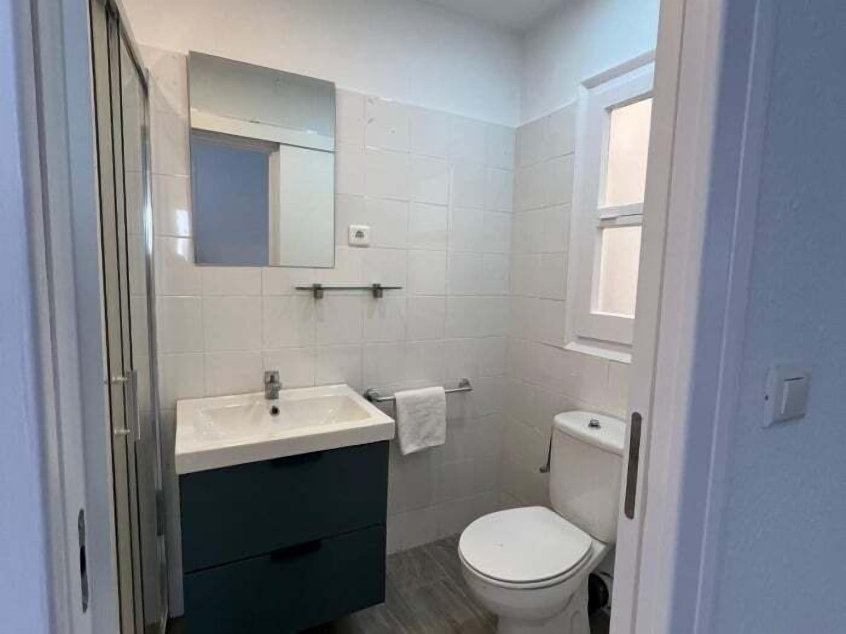 Une petite salle de bain moderne avec un lavabo blanc, un meuble de couleur foncée et des toilettes blanches.