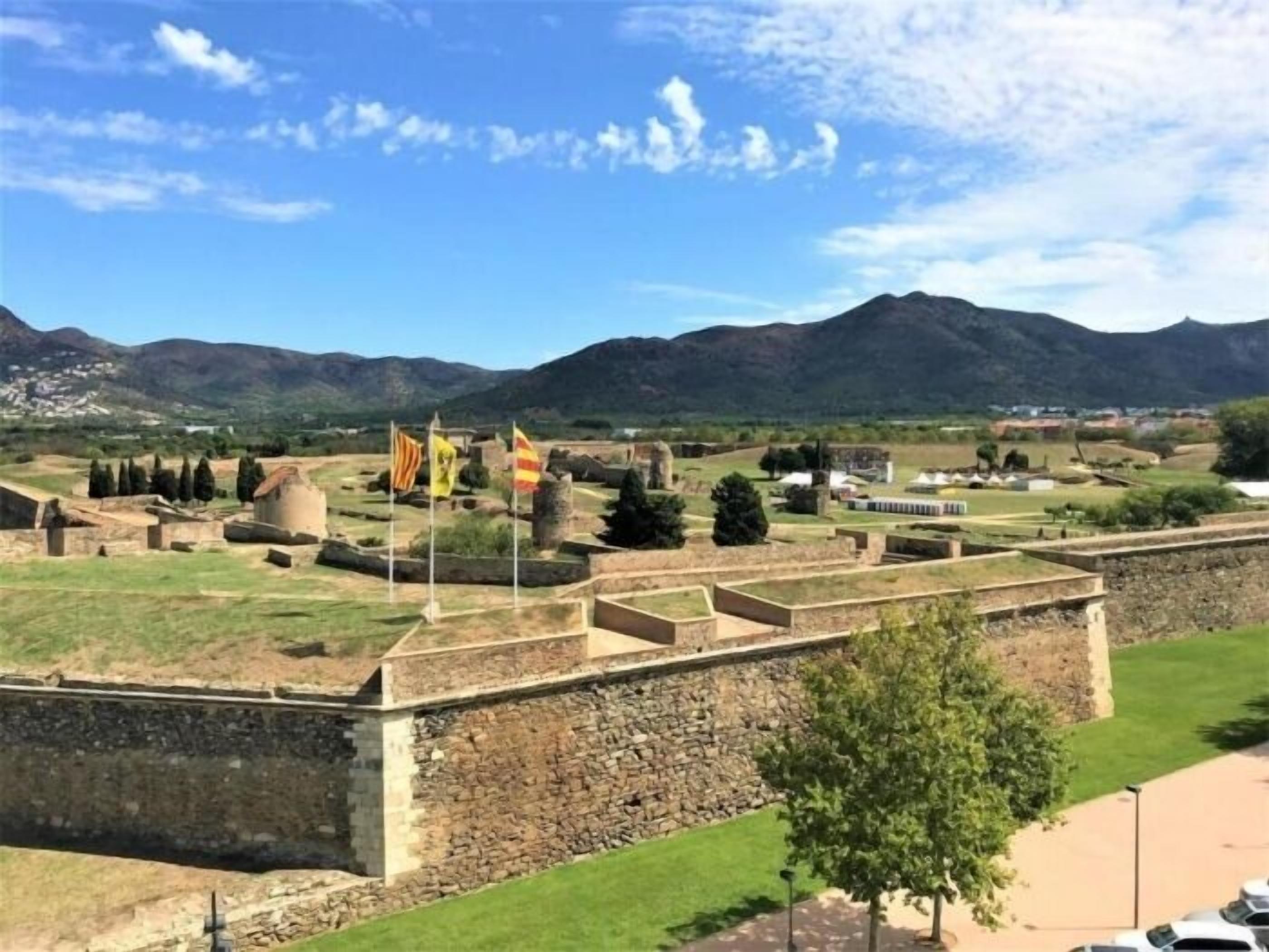 Un site historique abritant des ruines antiques, des murs de pierre et des drapeaux.