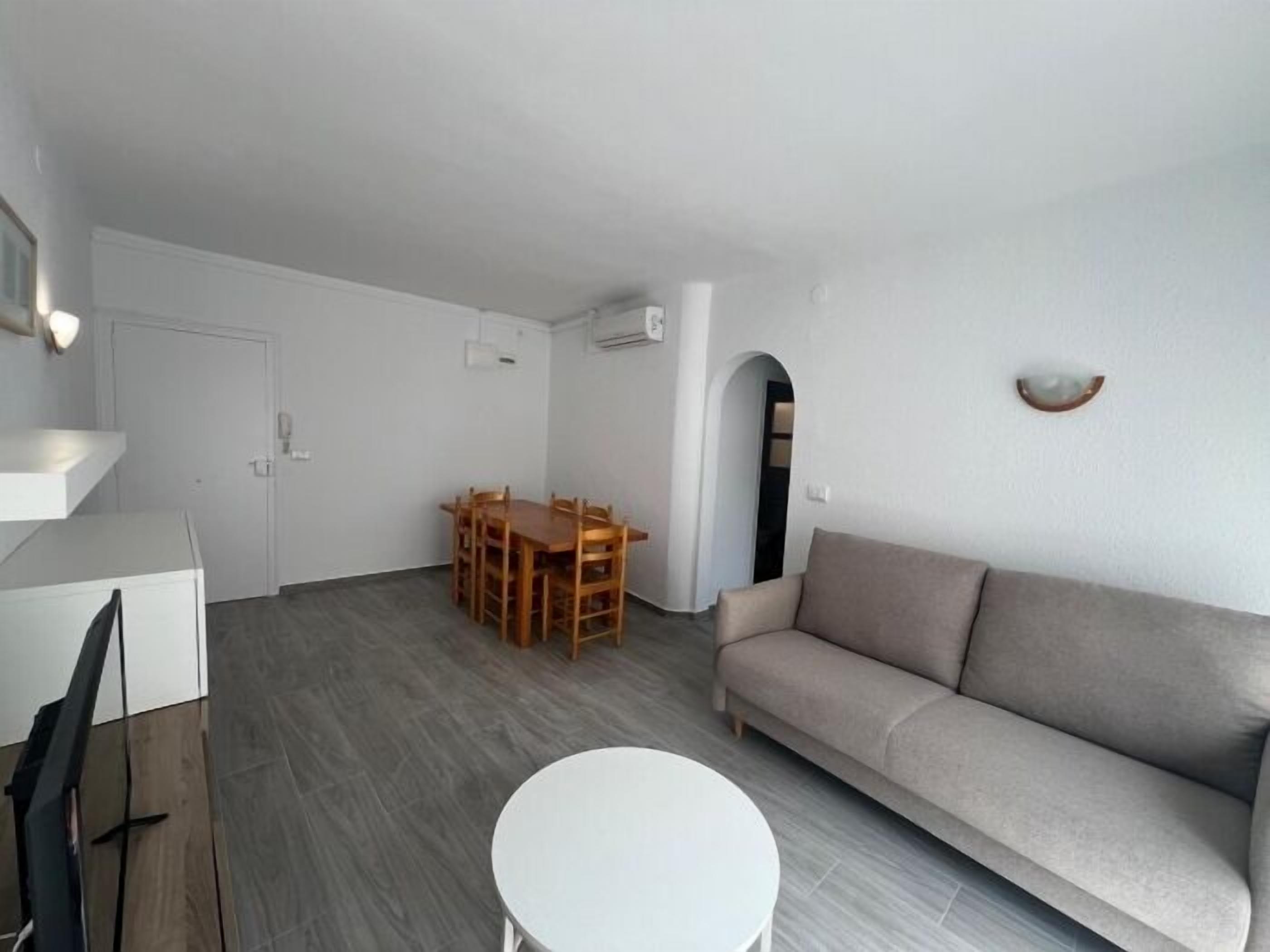 A modern living room with a sofa, a dining table with chairs, and a small white table.