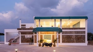 A modern building with a covered entrance, a staircase, and a motorcycle parked in front.