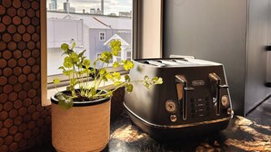 A toaster on a kitchen counter with a view of a cityscape and a tower in the background. - Stylish Freemans Bay Stay (Auckland)
