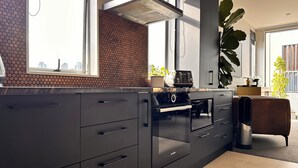 A modern kitchen with a large window, a built-in oven, and a backsplash with a circular pattern. - Stylish Freemans Bay Stay (Auckland)