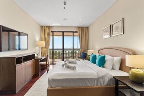 Ein Hotelzimmer mit Bett, Schreibtisch, Stuhl, Fernseher und einem Balkon mit Blick.
