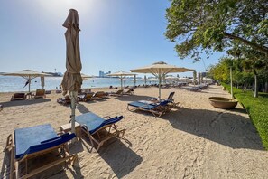 A beach with sun loungers, umbrellas, and a clear view of the sea.