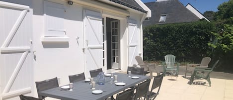 An outdoor patio with a table set for four, surrounded by chairs.