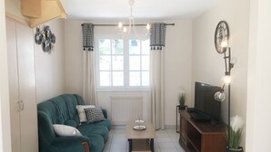 Una sala de estar con un sofá color turquesa, una mesa de centro de madera, un televisor sobre un mueble de madera y una lámpara de araña.