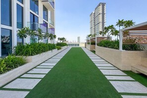 Un bâtiment moderne doté d’une pelouse artificielle verdoyante et de jardinières contenant des plantes.