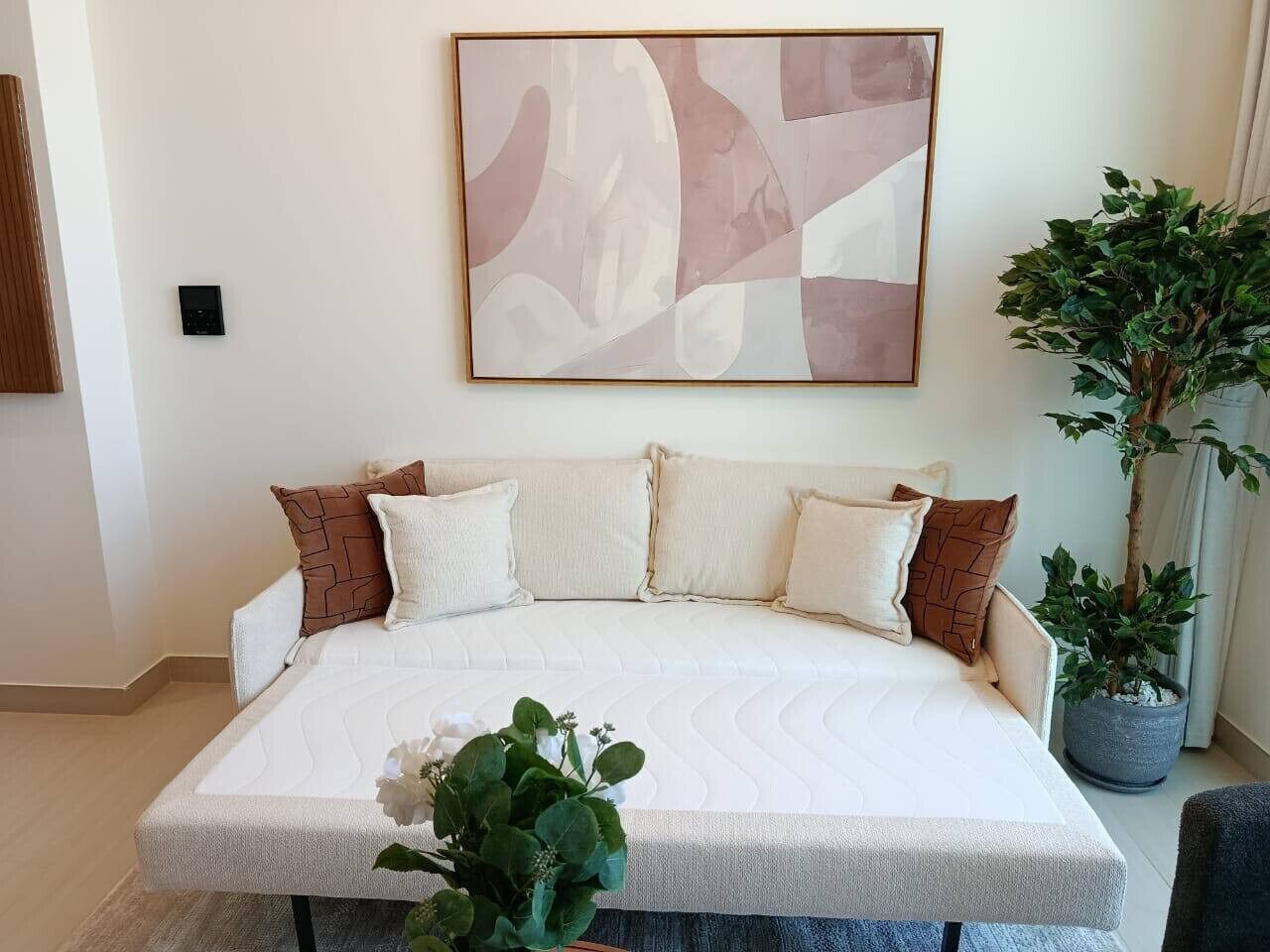 Una camera da letto moderna con un letto grande, un quadro astratto minimalista e una pianta in vaso.