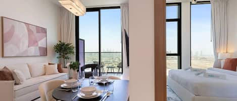 Una habitación de hotel moderna con zona de comedor, sofá y cama con vistas a la ciudad.