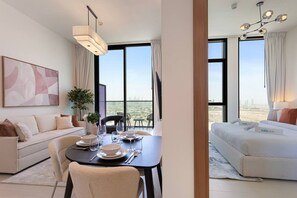 A modern hotel room with a dining area, a sofa, and a bed with a city view.