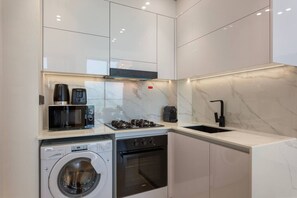 Een moderne keuken met een ingebouwde wasmachine, oven en koffieapparaat.