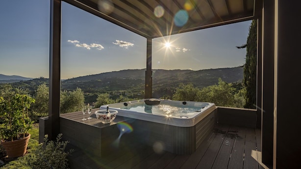 Ein Whirlpool auf einer Holzterrasse mit Blick auf eine Berglandschaft.